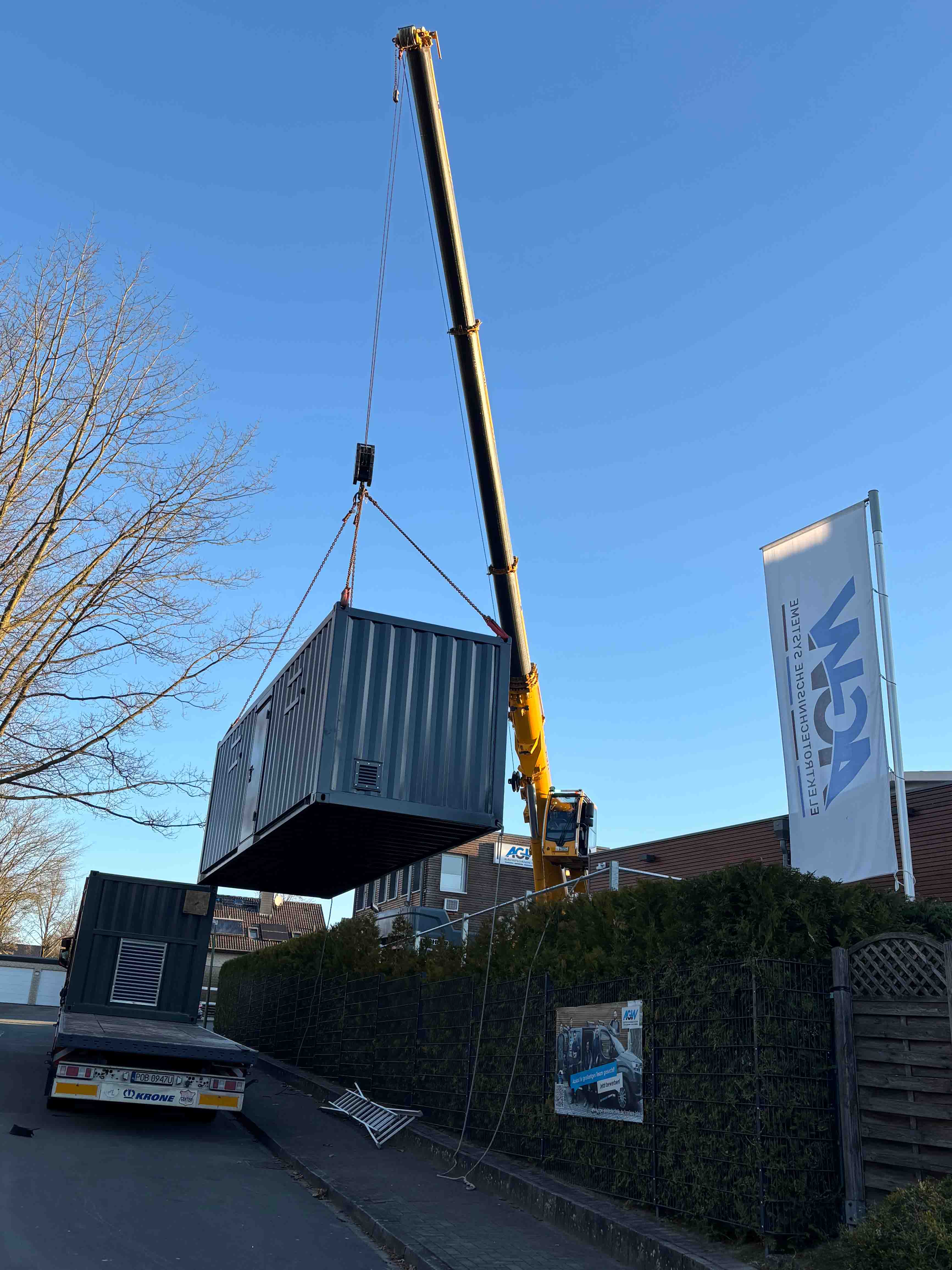 Ein Krank setzt den Überseecontainer auf das Firmengelände